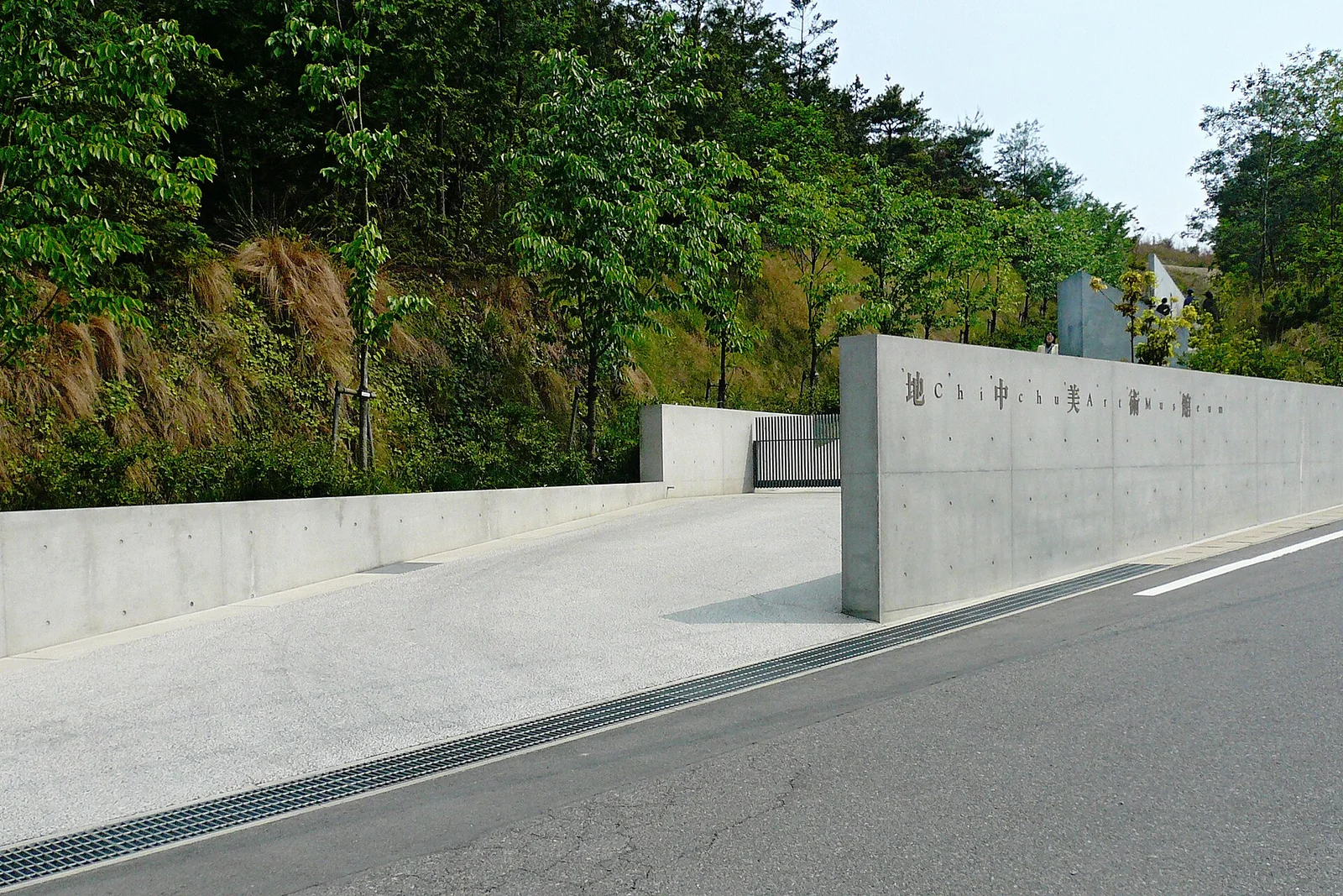 远眺地中美术馆(2007年):建筑的大半隐于地下,地面只留下混凝土的切口与斜坡 · 图像文件署名:663highland;CC BY 2.5;网页缩放,原始文件保留。