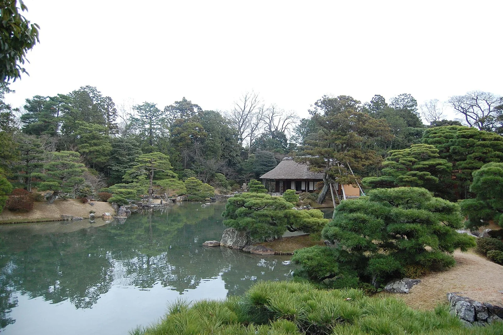 自月波楼隔池望松琴亭：茅葺入母屋顶与皮付柱的茶室，被20世纪的现代主义者读作'古典的现代性'。 · 图像文件署名：Raphael Azevedoo Franca；Public domain；网页缩放，原始文件保留。