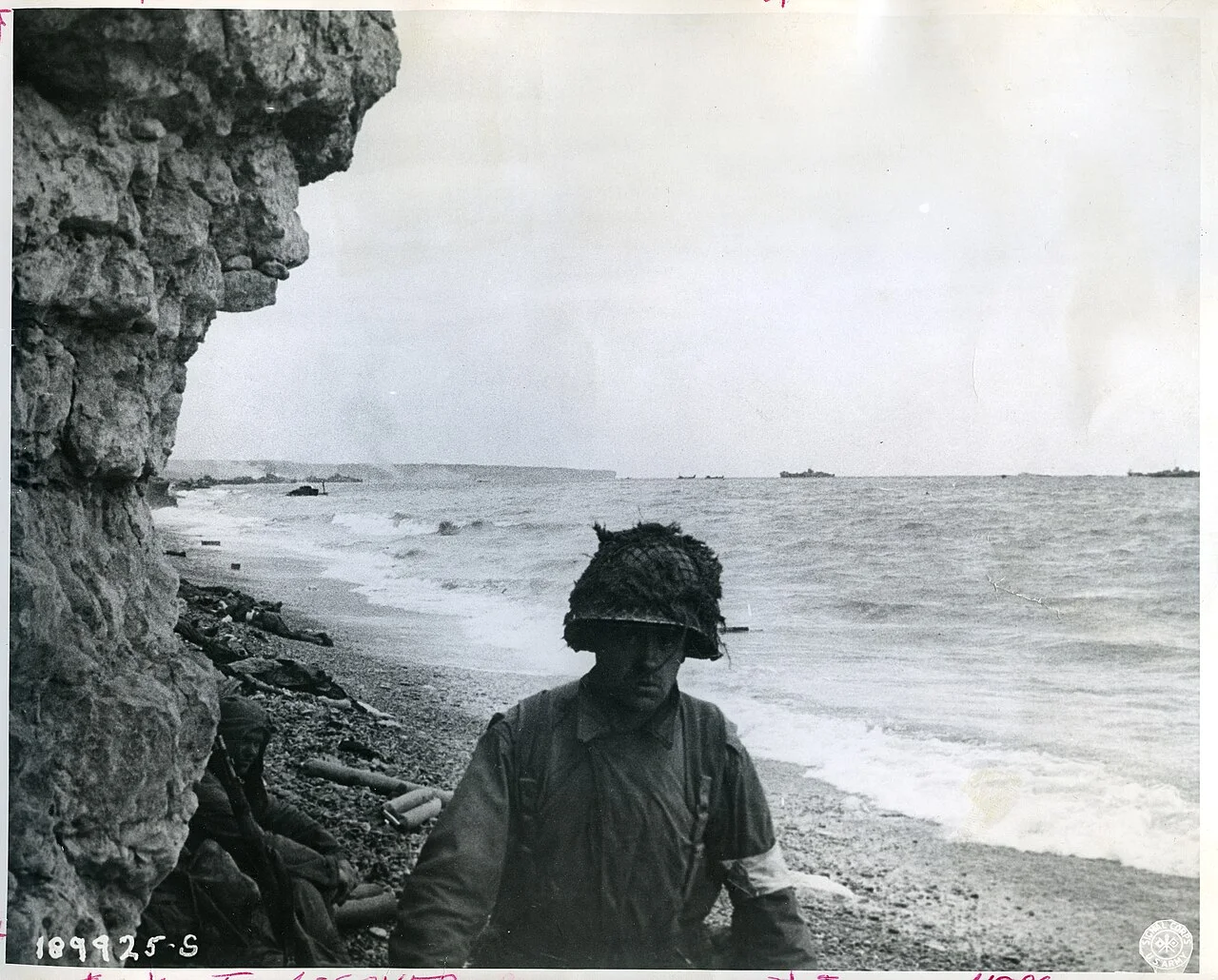 美国陆军通信兵摄,公有领域——军医在奥马哈海滩为伤兵包扎,1944 年 6 月 6 日(替代图)