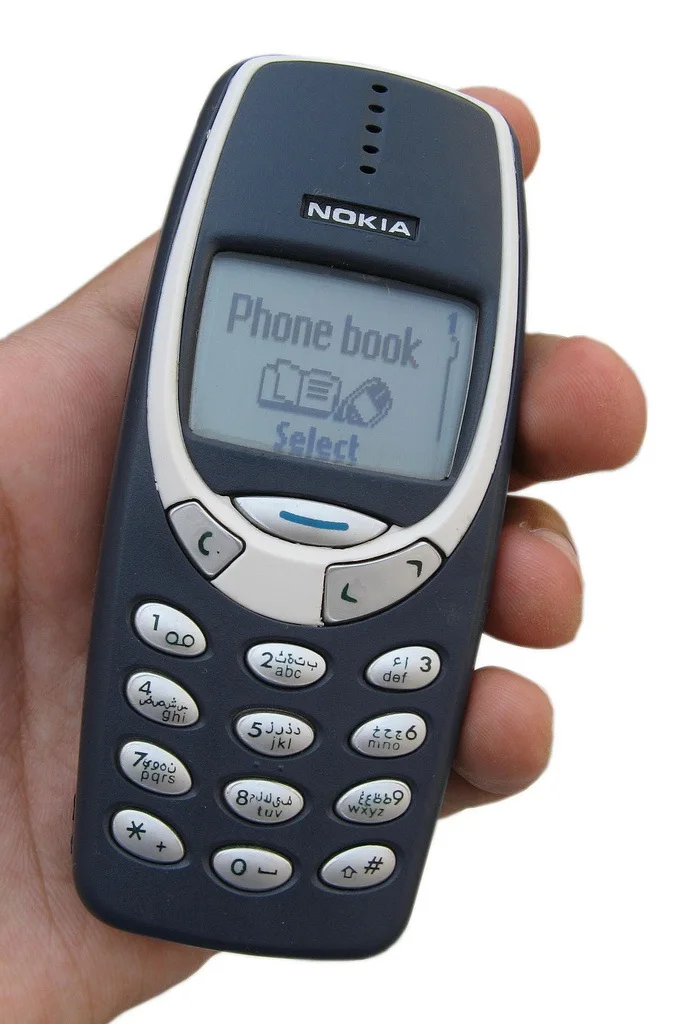 手心里的 Nokia 3310：轻、圆、手感扎实——传说的物理基础。 Asimzb / Wikimedia Commons, CC BY-SA 3.0。 · 图像文件署名：Asimzb；CC BY-SA 3.0；网页缩放，原始文件保留。