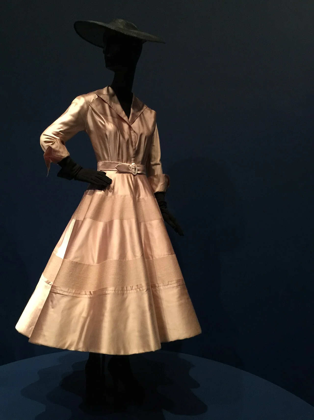 Dior 1948年春夏粉丝绸晚装裙。1947年确立的剪影语言——丰盈下摆与束细腰身——在次年系列中延续。 · 图像文件署名：Laura Blanchard from Philadelphia, USA；CC BY-SA 2.0；网页缩放，原始文件保留。
