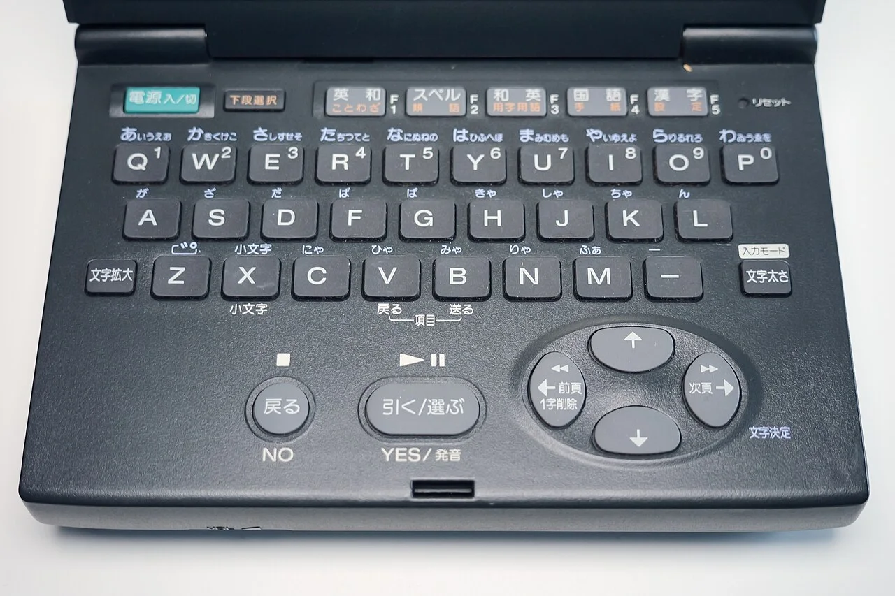 Data Discman DD-85 的键盘面：检索词的输入区被设计成完整的 QWERTY。图中机种为 1996 年发售的 DD-85（原计划的 DD-8 键盘图无可用授权数据，改用同系列 DD-85 替代，谨此说明）。 ThisDoesNotCompute / Wikimedia Commons, CC BY 4.0。 · 图像文件署名：ThisDoesNotComp；CC BY 4.0；网页缩放，原始文件保留。