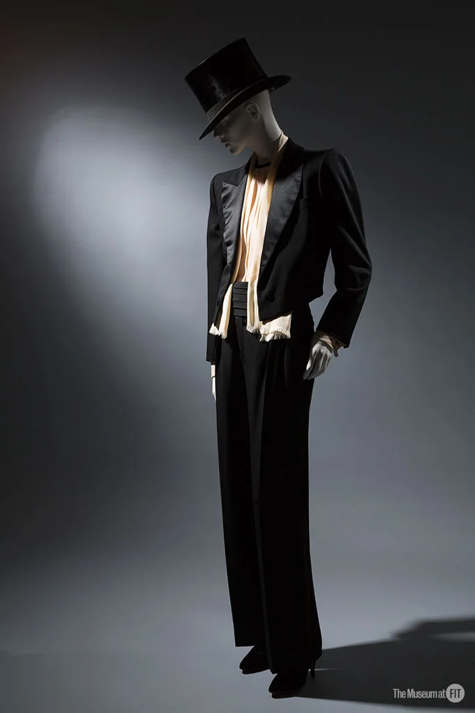 FIT 博物馆藏 Saint Laurent Rive Gauche 礼服套装。领口的女性曲线、收窄的腰线、拉长腿部的裤型。 · 图像文件署名：Museum at FIT；CC BY-SA 2.0；网页缩放，原始文件保留。