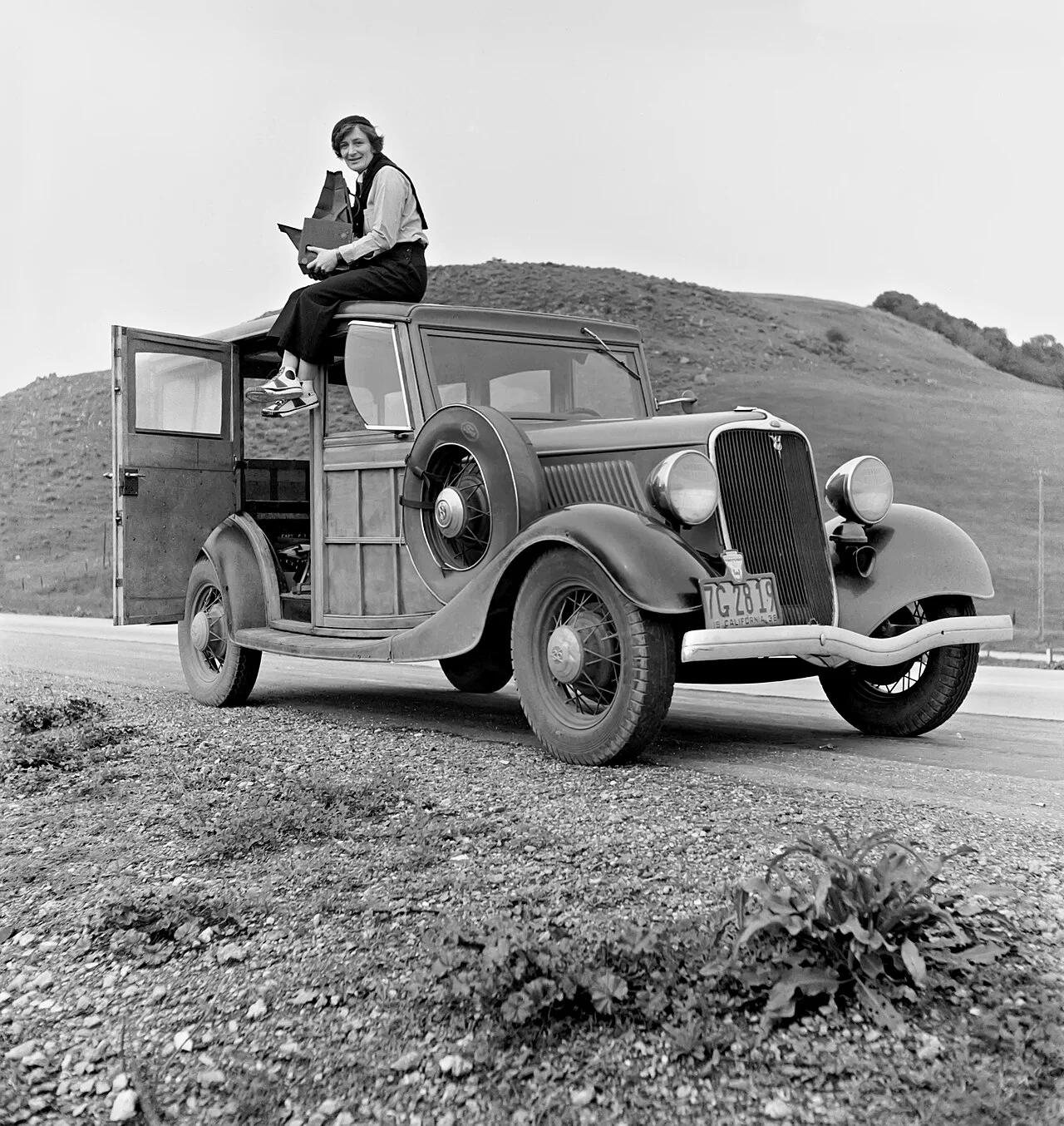 Rondal Partridge 摄,公有领域——Dorothea Lange atop automobile in California(注意:此为兰格坐在车上的工作照)