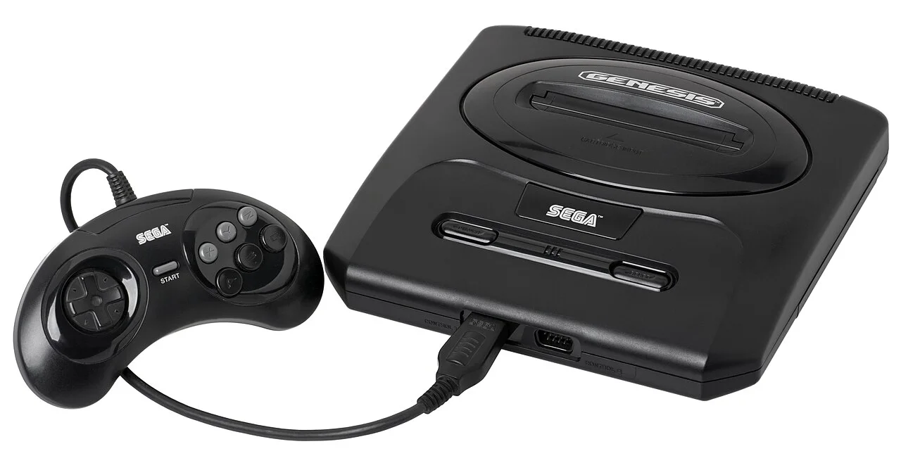 北美版 Sega Genesis Model 2 主机与六键手柄，摄影 Evan-Amos，CC BY-SA 3.0，图片来源：Wikimedia Commons。注意：图为 1993 年前后的第二代 Genesis（Model 2），非 1989 年初代 Genesis，与「Blast Processing」广告年代（1992 年前后）的主力机型亦有代际差异。
