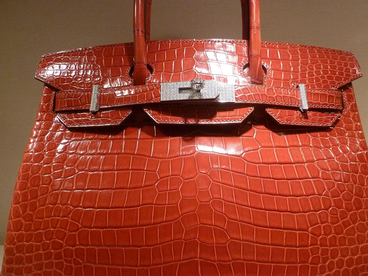 鳄鱼皮Birkin。珍稀皮革版本是配货与溢价现象最集中的品类，也是2015年柏金本人抗议的对象。 · 图像文件署名：Ohconfucius；CC BY 3.0；网页缩放，原始文件保留。