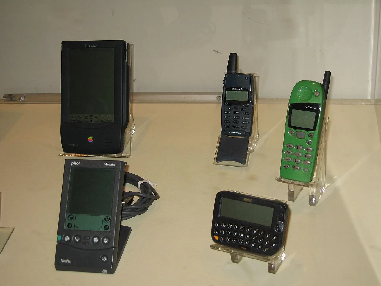一组1990年代末至2000年代初的移动设备合影（含一台早期 BlackBerry，与 Apple Newton、Ericsson T28、Nokia 3100、Palm Pilot 同框）——替身图：并非 850 本机特写，用于呈现其同时代设备生态。图：Shiny Things / Wikimedia Commons，CC BY 2.0。